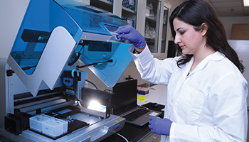 Female researcher in lab coat closing machine